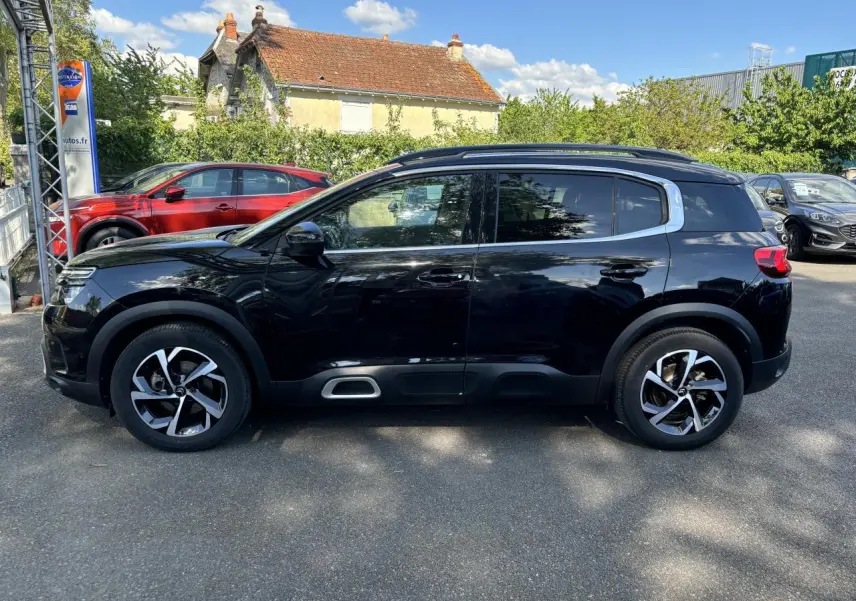 Profil côté gauche d'un Citroën C5 Aircross noir métallisé, avec ses jantes distinctives et ses vitres surteintées.