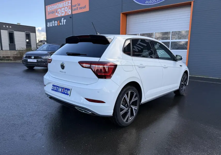 Volkswagen Polo blanc pur en 3/4 arrière droit, vitres surteintées et jantes alliage 17 pouces R-Line visibles.