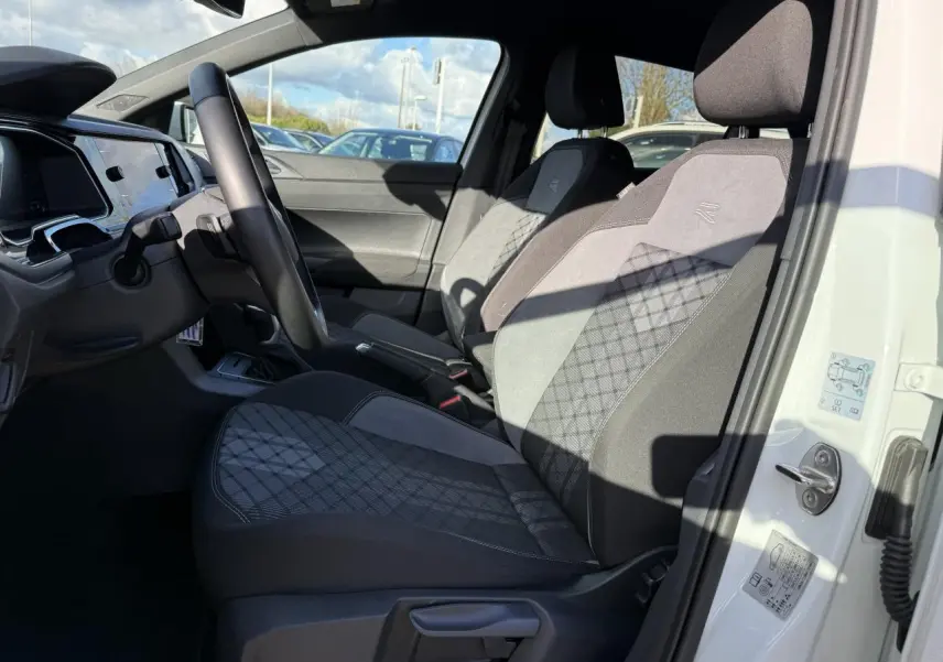 Intérieur côté conducteur d'une Volkswagen Polo blanc pur 2025, sièges R-Line en tissu gris avec motifs losanges.