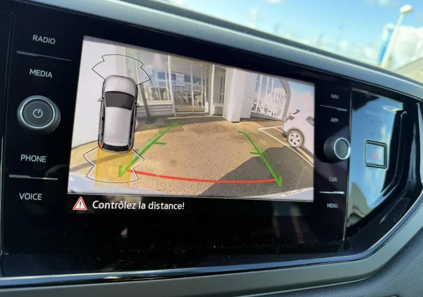 Écran de la caméra de recul affichant l’aide au stationnement d’une Volkswagen Polo blanche pure 2025.