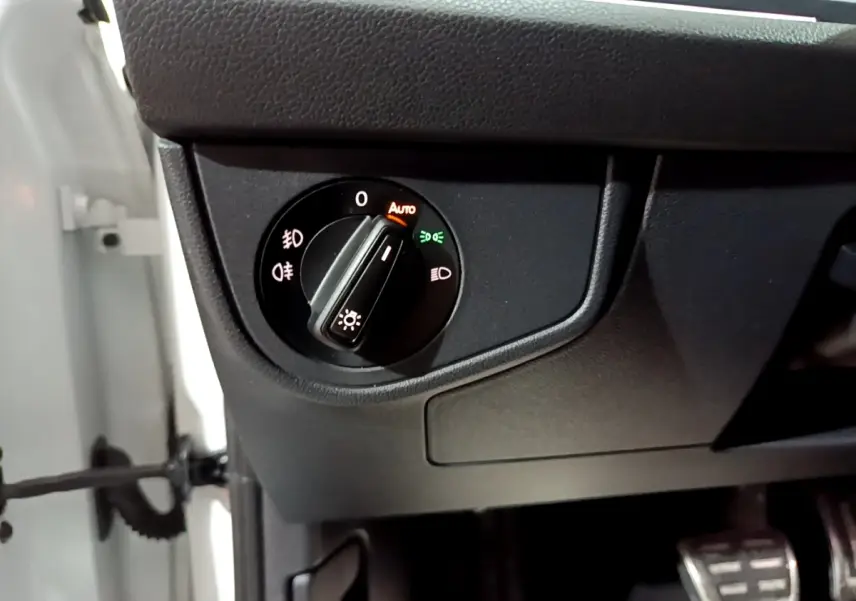 Gros plan sur la commande des feux du tableau de bord intérieur du Volkswagen Taigo blanc, version R-Line 2022.