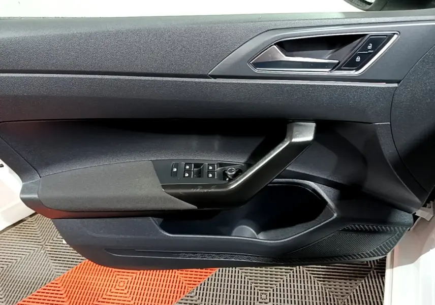 Vue intérieure du panneau de porte avant gauche du Volkswagen Taigo blanc, avec commandes de vitres et verrouillage.