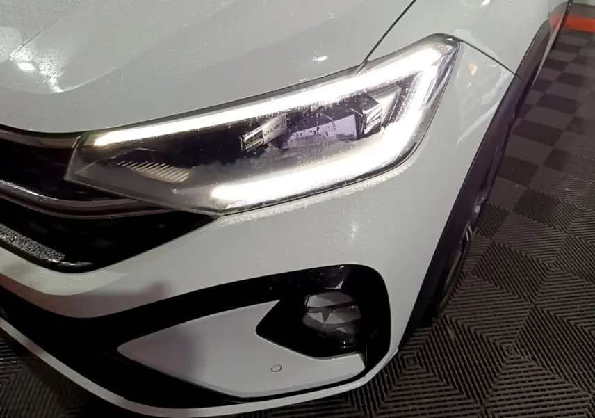 Gros plan sur le phare avant droit blanc du Volkswagen Taigo 2022 avec éclairage LED et antibrouillard intégré.