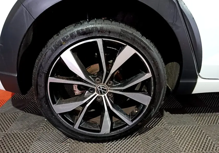 Gros plan sur la roue avant droite d’un Volkswagen Taigo blanc, jante alliage noir et argentée R-Line.