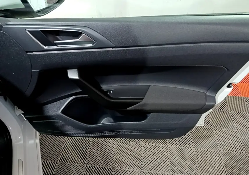 Vue rapprochée de la porte avant gauche blanche du Volkswagen Taigo 2022 avec poignée intérieure noire et garniture texturée.