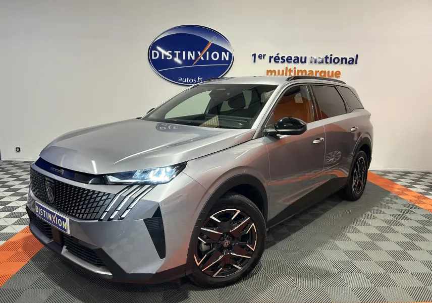 Peugeot 5008 gris Artense en 3/4 avant droit, avec calandre distinctive et jantes noires brillantes.