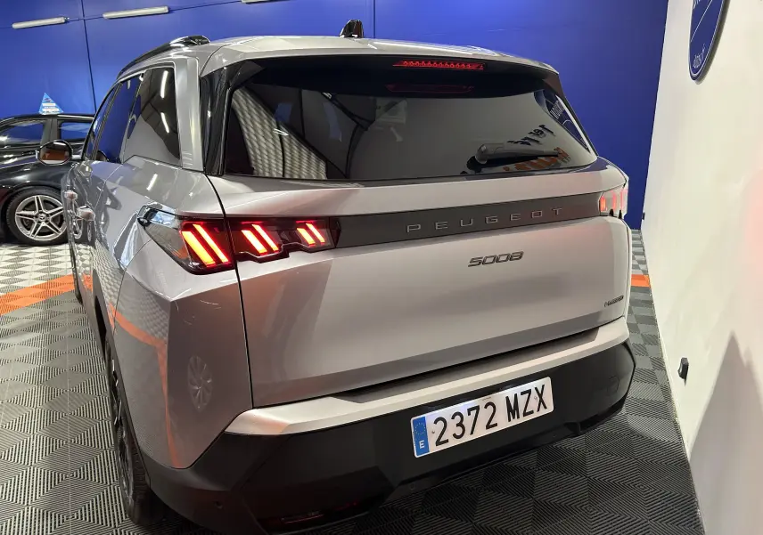 Vue 3/4 arrière droite du Peugeot 5008 gris Artense avec feux arrière allumés dans un garage.