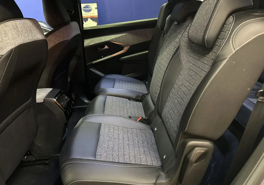 Vue latérale intérieure des sièges arrière en tissu gris et cuir noir du Peugeot 5008 III Hybrid 145 Allure 2025.