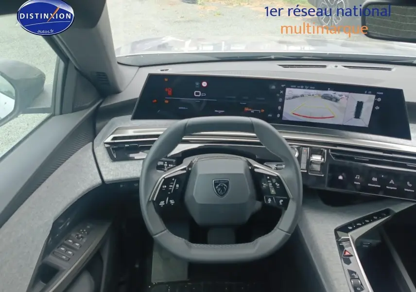 Vue intérieure centrée sur le volant Peugeot 5008 gris Artense avec tableau de bord numérique et caméra de recul affichée.