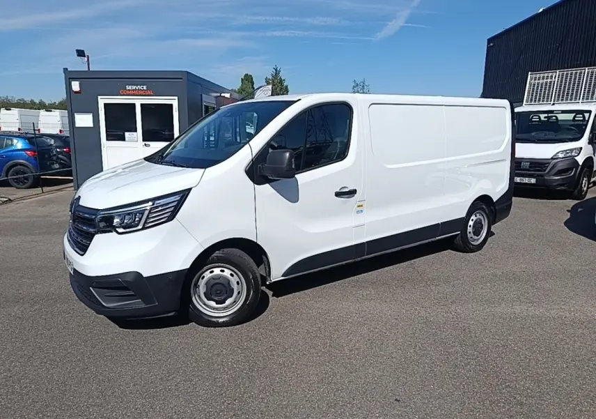 Renault Trafic Fourgon blanc en 3/4 avant droit, avec jantes acier et pare-chocs noirs, stationné en extérieur.