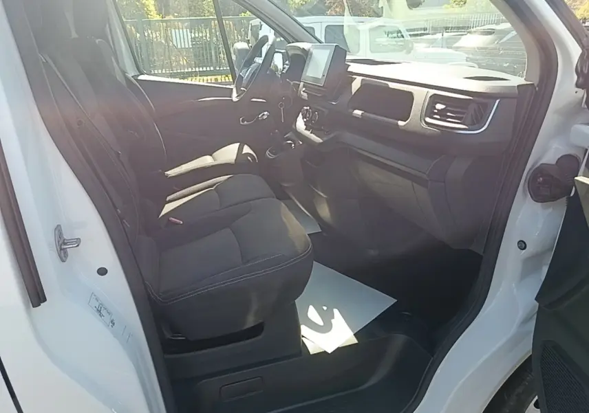 Vue intérieure côté conducteur du Renault Trafic Fourgon blanc 2023, montrant les sièges et le tableau de bord.