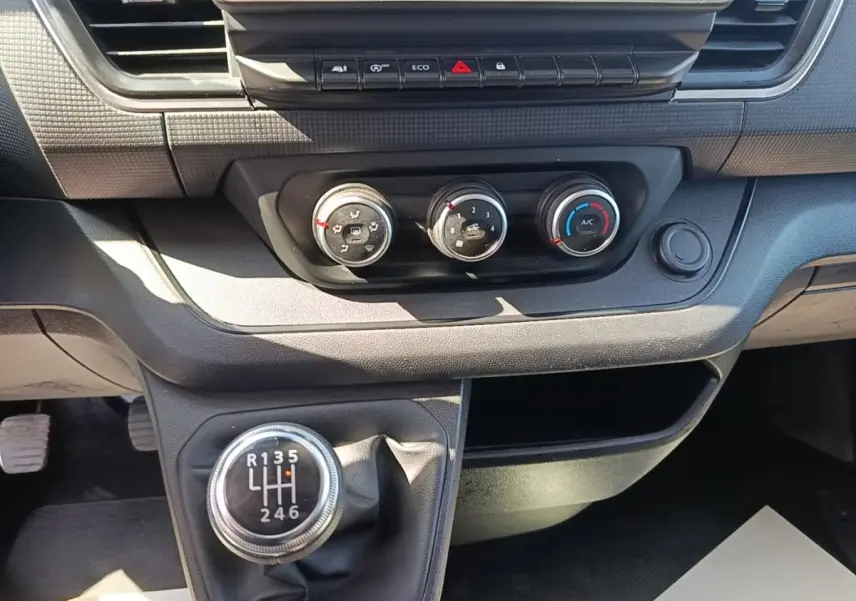 Vue rapprochée de la console centrale du Renault Trafic Fourgon 2023, avec levier de vitesses manuel et commandes de climatisation.