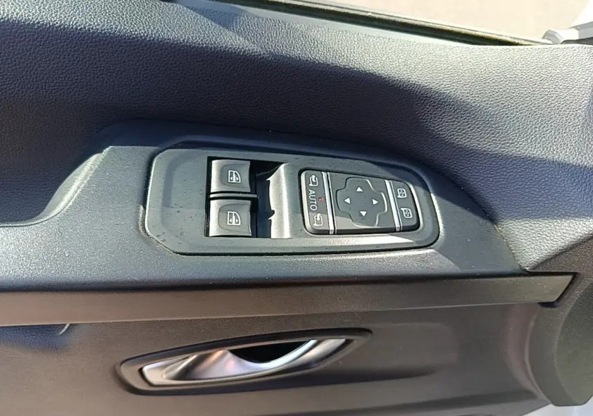 Gros plan sur les commandes de lève-vitres et rétroviseurs électriques sur la porte côté conducteur du Renault Trafic blanc.