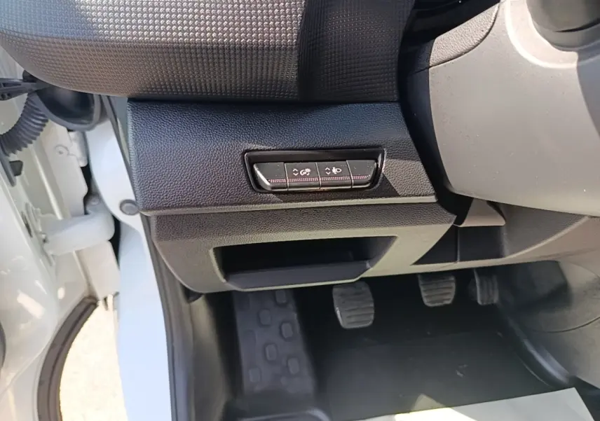 Vue intérieure côté conducteur du Renault Trafic Fourgon blanc 2023, avec pédales et commandes sous le tableau de bord.