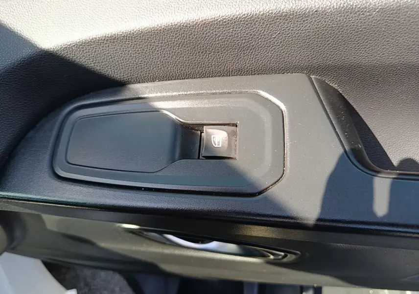 Gros plan sur le bouton de commande de lève-vitre côté conducteur dans l’habitacle du Renault Trafic Fourgon blanc 2023.