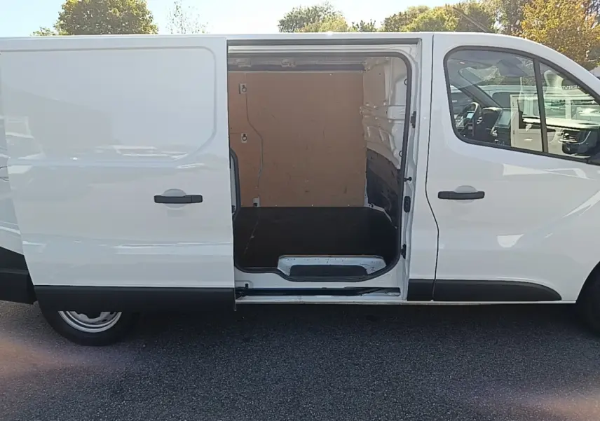 Vue latérale droite d’un Renault Trafic Fourgon blanc 2023 avec porte coulissante ouverte montrant l’espace de chargement vide.