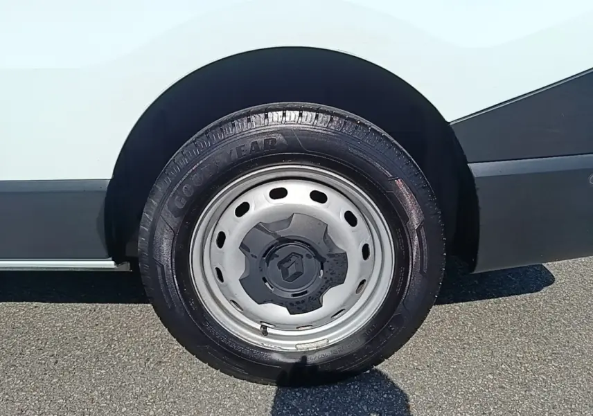 Gros plan sur la roue arrière droite en jante acier grise du Renault Trafic Fourgon blanc, avec logo Renault au centre.