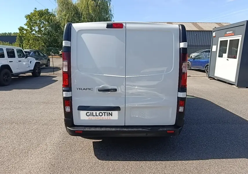 Vue arrière d'un Renault Trafic Fourgon blanc 2023 avec portes battantes et feux arrière verticaux.