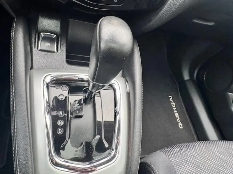 Le levier de boîte automatique noir du Nissan Qashqai 2015 vu de dessus avec tapis de sol marqué Qashqai.