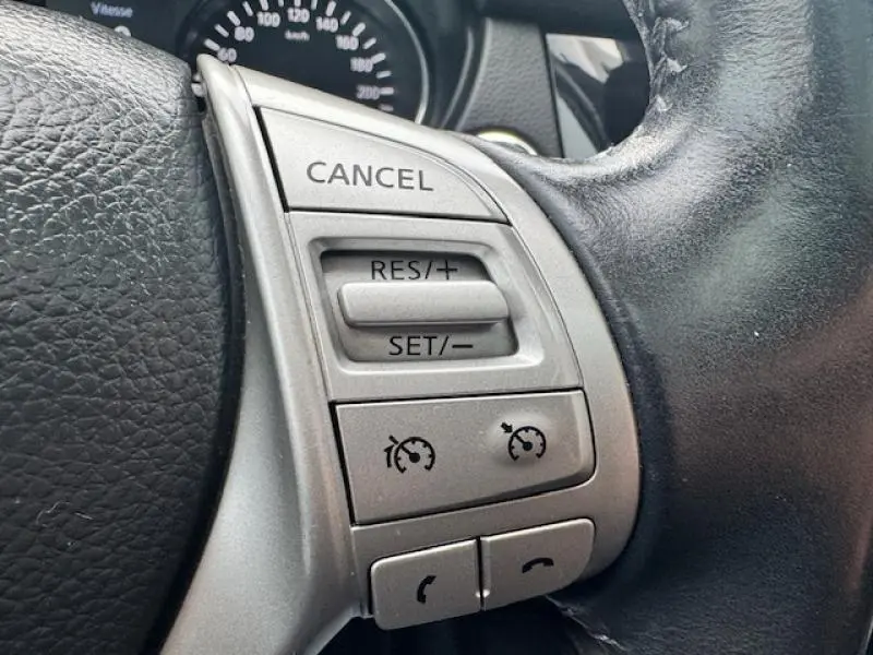 Gros plan sur les commandes du régulateur de vitesse au volant cuir noir du Nissan Qashqai gris Squale, 2015.