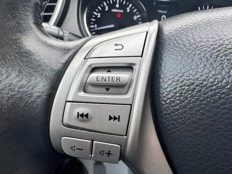Gros plan sur les commandes multifonctions argentées du volant cuir côté gauche du Nissan Qashqai gris Squale de 2015.