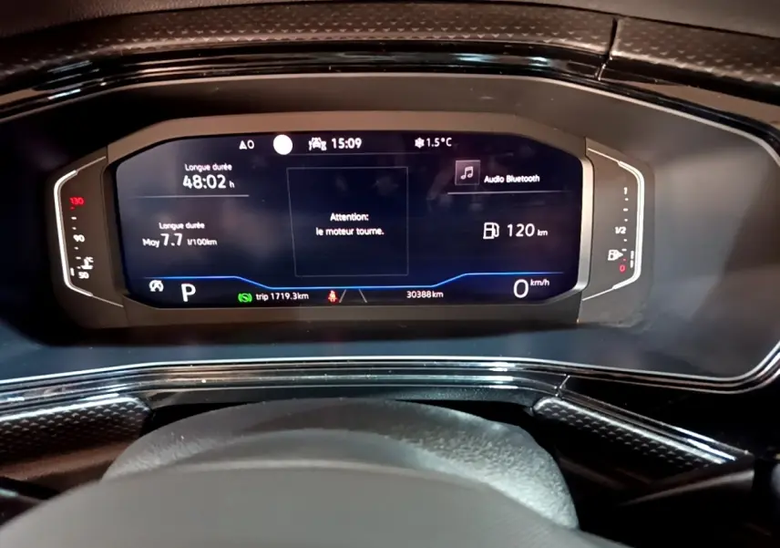 Vue rapprochée du combiné d'instruments numérique du Volkswagen T-Cross 2023 affichant vitesse, autonomie et alertes moteur.