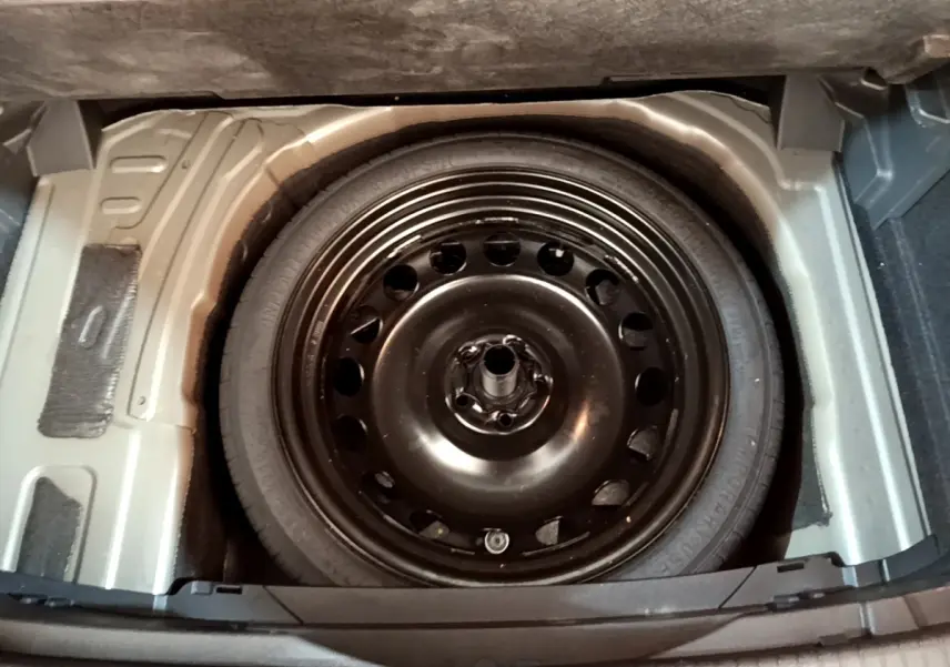Roue de secours noire vue de dessus dans le coffre d’un Volkswagen T-Cross gris foncé 2023.