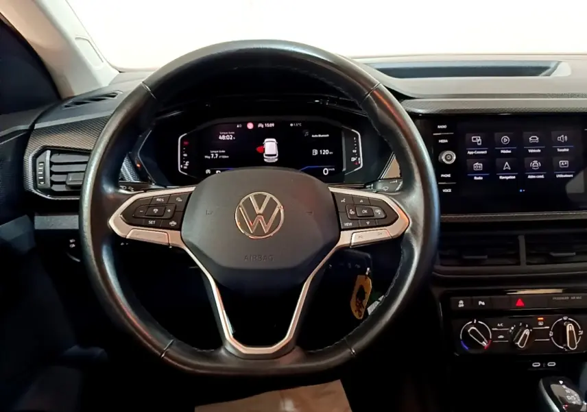 Vue rapprochée du volant cuir multifonctions noir du Volkswagen T-Cross 2023 avec tableau de bord digital et écran tactile central.
