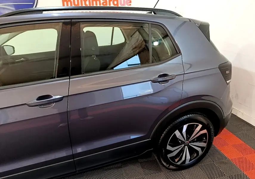 Vue latérale droite du Volkswagen T-Cross gris foncé 2023, mettant en valeur la porte arrière et la roue arrière au design moderne.