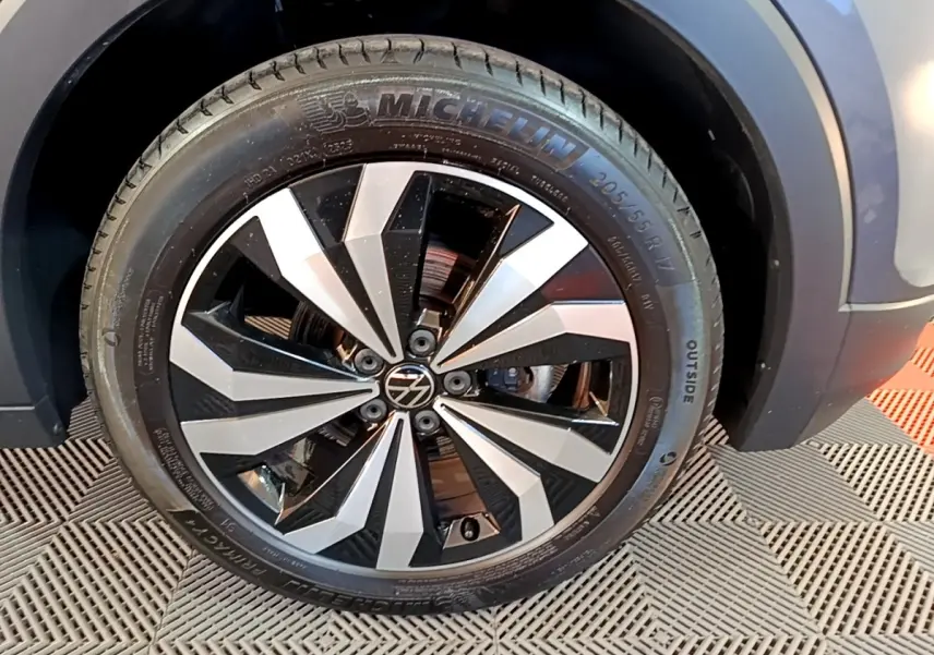 Gros plan sur la roue avant droite du Volkswagen T-Cross gris foncé, avec jante alliage bicolore et pneu Michelin.