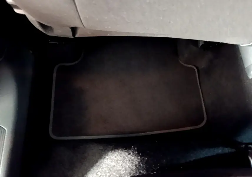 Vue du sol côté passager avant du Volkswagen T-Cross gris foncé, avec tapis de sol en tissu noir.