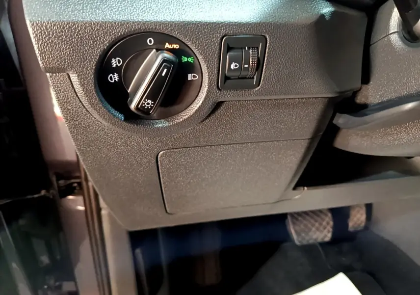 Gros plan sur le panneau de commande des phares côté gauche du Volkswagen T-Cross gris foncé, intérieur conducteur.