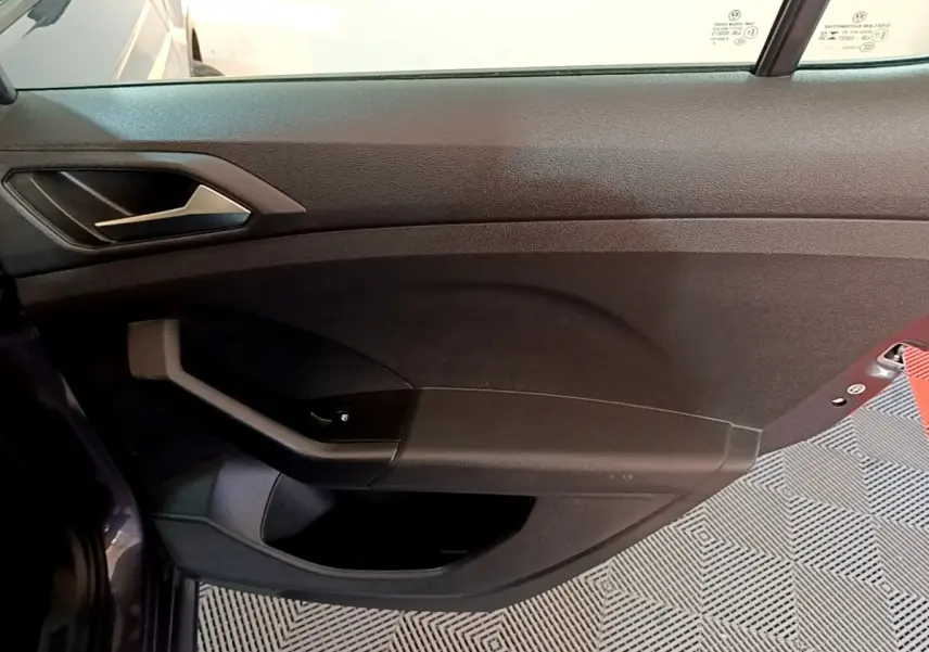 Vue intérieure côté gauche de la porte avant d’un Volkswagen T-Cross gris foncé avec poignée et commande de vitre.