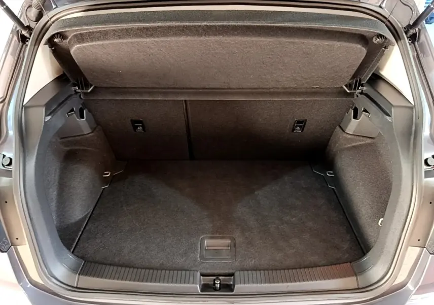Vue arrière ouverte du coffre gris foncé du Volkswagen T-Cross 2023, montrant l'espace de rangement vide et la tablette de séparation.