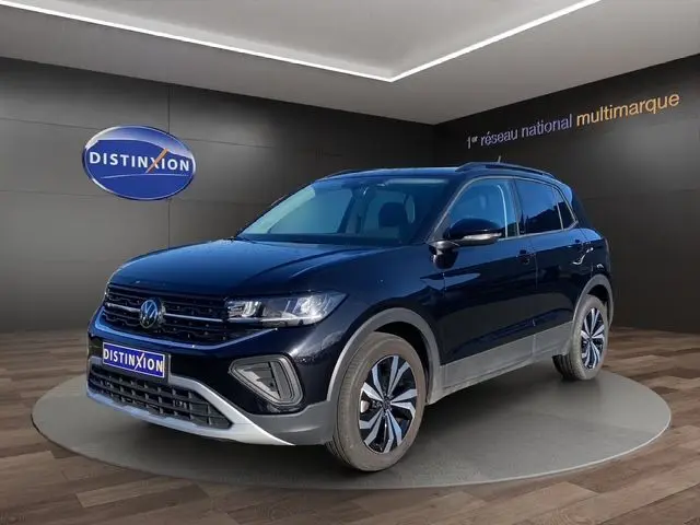 Volkswagen T-Cross noir en 3/4 avant droit, avec jantes alliage et calandre marquée, en showroom intérieur.
