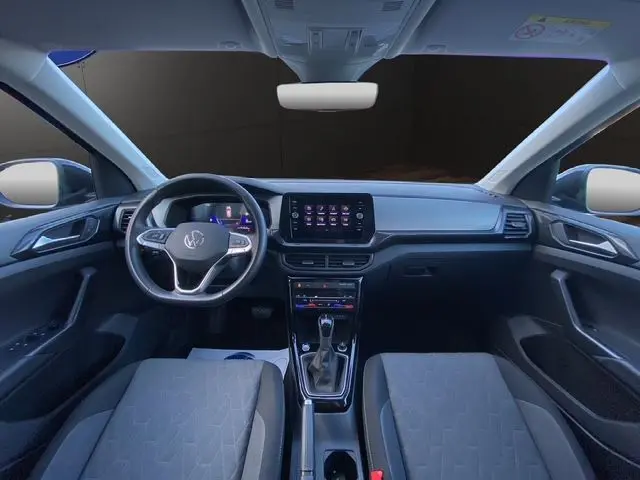 Vue intérieure avant du Volkswagen T-Cross noir 2025, tableau de bord moderne avec écran tactile central et volant multifonction.