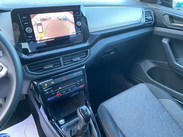 Vue intérieure côté passager du tableau de bord et console centrale noire du Volkswagen T-Cross 1.0 TSI avec écran tactile affichant la caméra de recul.