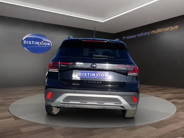 Vue arrière d'un Volkswagen T-Cross noir 2025 sur plateforme tournante, avec feux LED et logo distinctif visible.