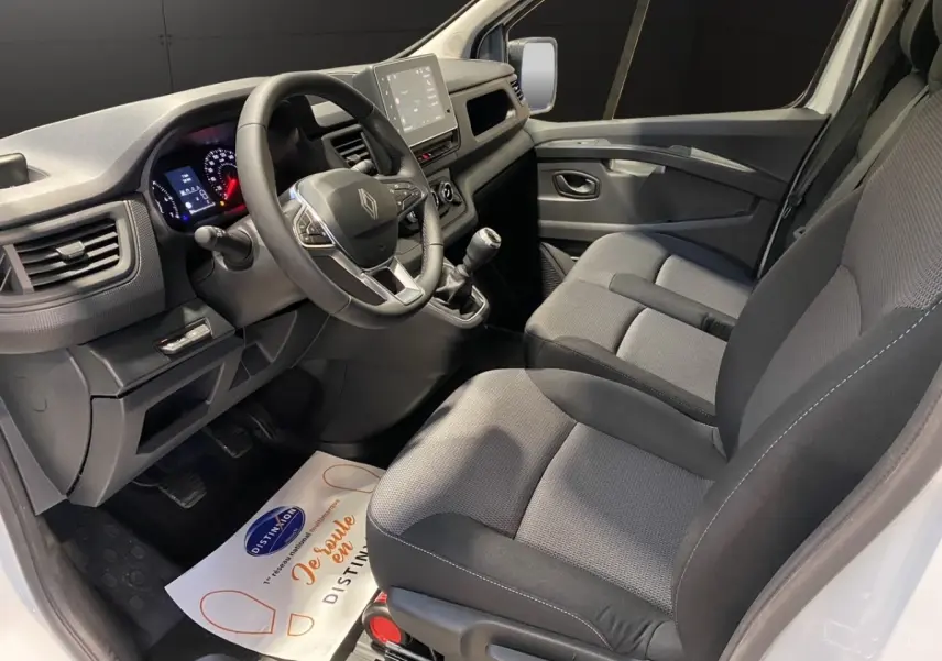 Vue intérieure côté conducteur du Renault Trafic Fourgon blanc 2025, montrant le volant multifonctions et la console centrale.
