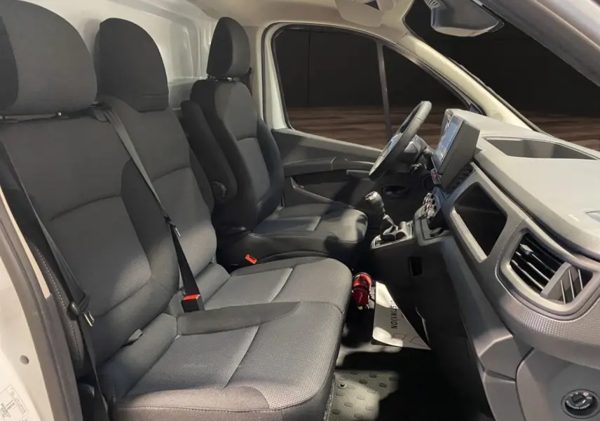 Vue intérieure côté droit du Renault Trafic Fourgon blanc, montrant les sièges avant et le tableau de bord avec volant multifonctions.