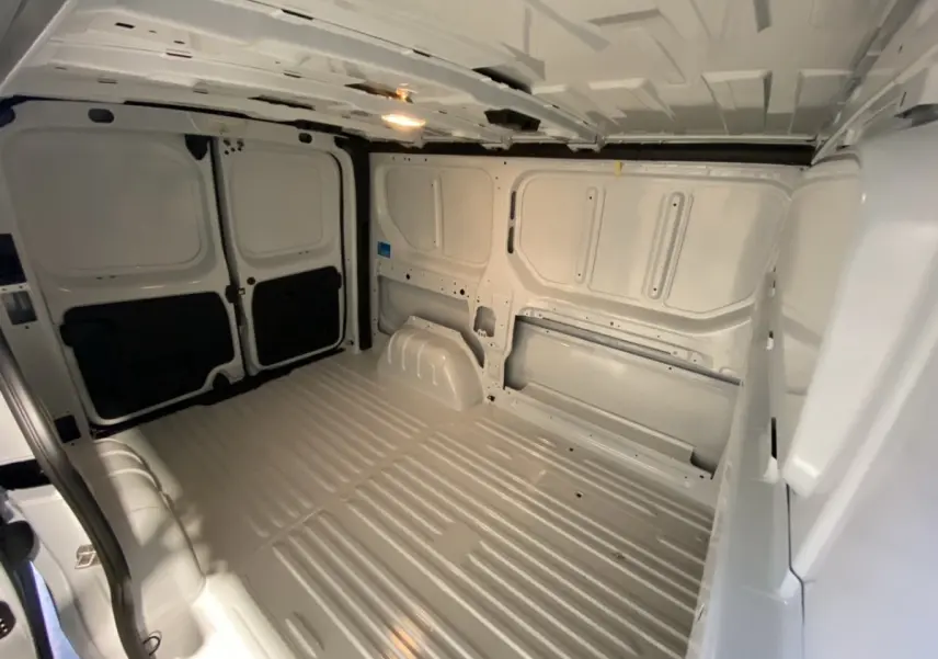 Vue intérieure du fourgon Renault Trafic blanc, montrant l’espace de chargement vide avec cloison pleine à l’arrière.