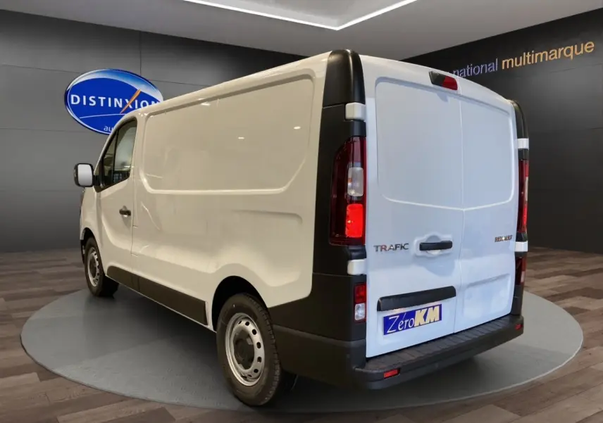 Vue 3/4 arrière droite du fourgon blanc Renault Trafic L1H1 avec portes arrière fermées et jantes acier.