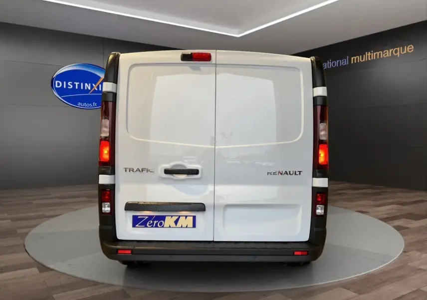 Vue arrière du Renault Trafic Fourgon blanc, portes battantes fermées avec feux arrière allumés en intérieur showroom.