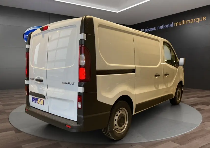 Vue 3/4 arrière droite du fourgon blanc Renault Trafic Fourgon L1H1 avec portes arrière battantes et feux arrière verticaux.
