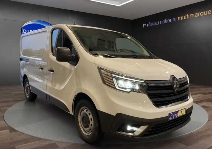 Renault Trafic Fourgon blanc en 3/4 avant droit, phares LED allumés et calandre noire distinctive.