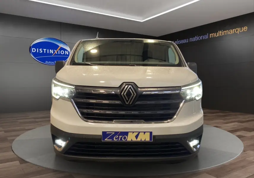 Vue frontale du Renault Trafic Fourgon blanc 2025 avec phares LED allumés en showroom.