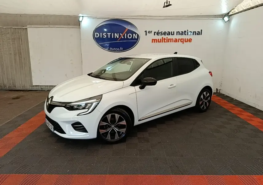 Renault Clio blanche vue 3/4 avant droit, avec jantes noires et rétroviseurs noirs dans un showroom.