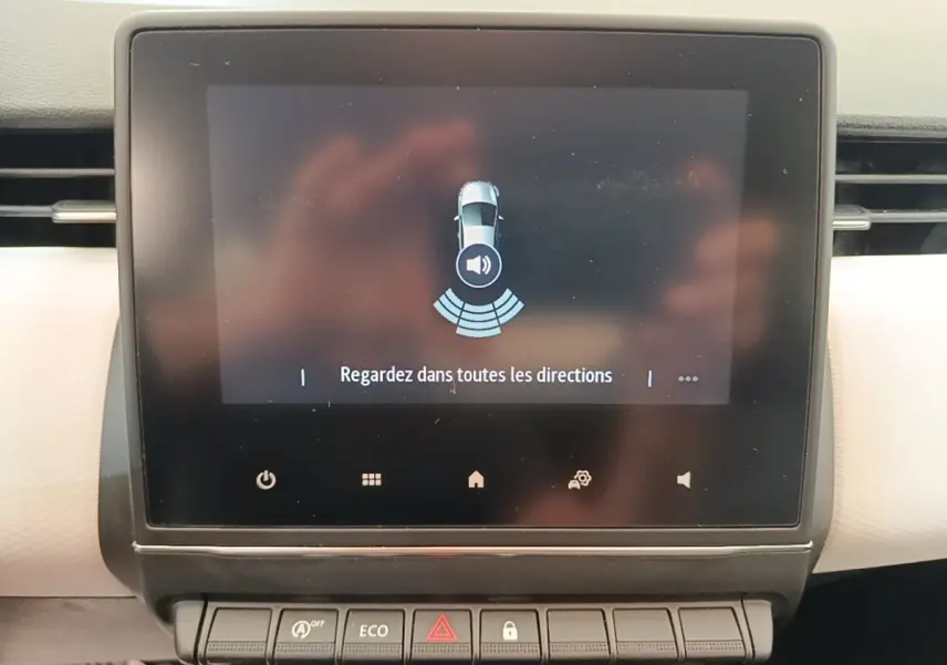 Écran tactile central de la Renault Clio blanc 2023 affichant une alerte de surveillance des alentours.