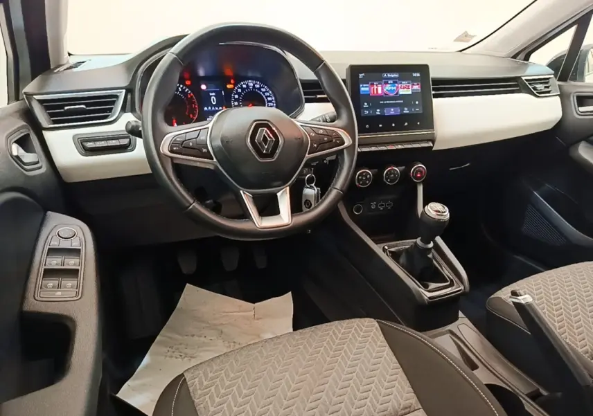Vue intérieure avant de la Renault Clio blanche 2023, volant cuir multifonctions et écran tactile central visible.