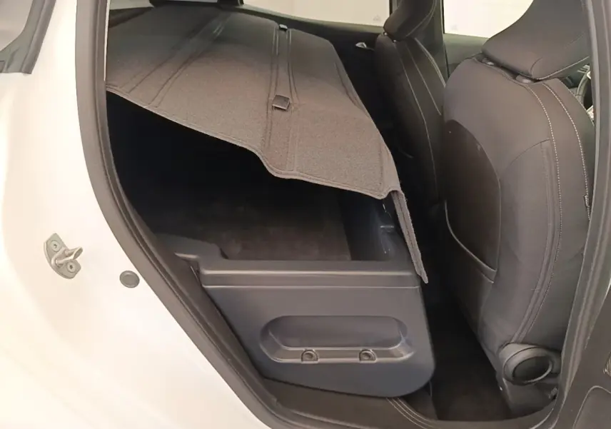 Vue intérieure côté gauche arrière de la Renault Clio blanche 2023, coffre sous banquette arrière relevé.